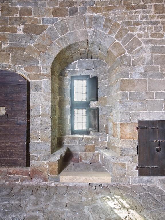 Vue intérieure de la tour Solidor : rez-de-chaussée, pièce intermédiaire, détail du mur sud, baie à double coussiège orientée vers le sud ; à droite, la porte d'un placard mural (ancienne poterne)