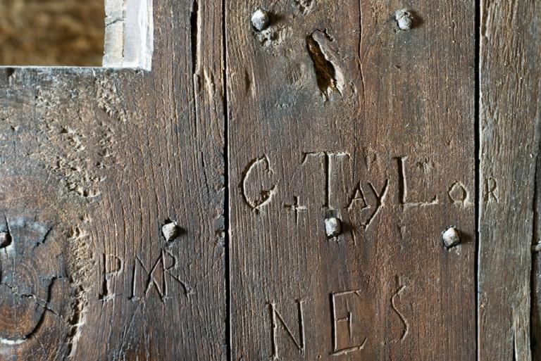 Vue intérieure de la tour Solidor : détail des graffitis de la porte du premier étage. On peut lire : G+TayLor ; PMR ; NES
