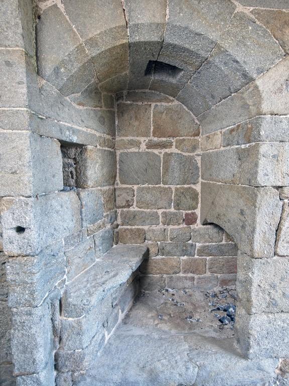 Vue intérieure de la tour Solidor : rez-de-chaussée, poste de garde implanté dans le passage d'entrée au nord. Il comprend un banc en pierre, une cheminée et une niche mural. Dans la voûte se trouve un assommoir accessible depuis le premier étage