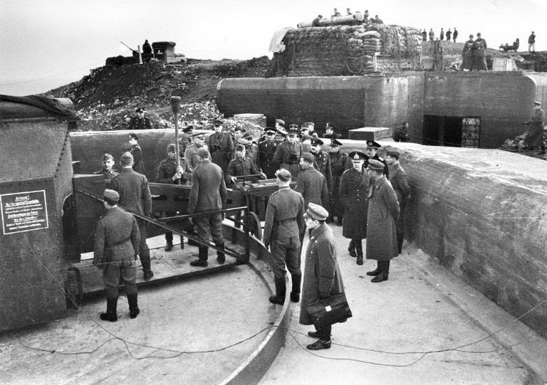 Vue d'une inspection des travaux de fortification de l'île Cézembre en présence d'une délégation japonaise : armement d'un canon de 19,4 cm, fin 1942-1943. En arrière-plan : un télémètre. Il s'agit d'une photographie de propagande nazie