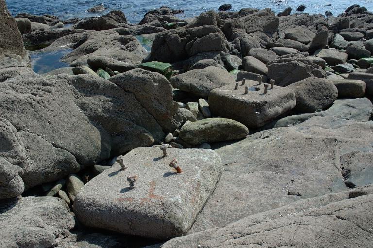 Vue de deux dés d'ancrage en pierre de taille de granite de la batterie basse sur la grève à marée basse (état en 2005). Dotés de quatre ou six tiges filetées, ces dés correspondent à de l'artillerie du 19e siècle