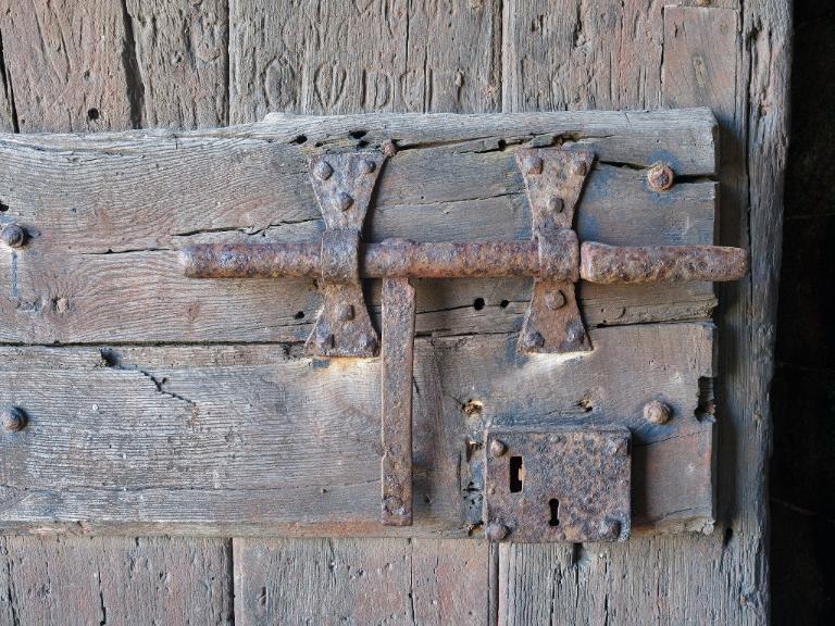 Vue de la tour Solidor : détail du dispositif de fermeture de la porte d'entrée (grand verrou et serrure). Des graffitis sont visibles sur le battant de la porte