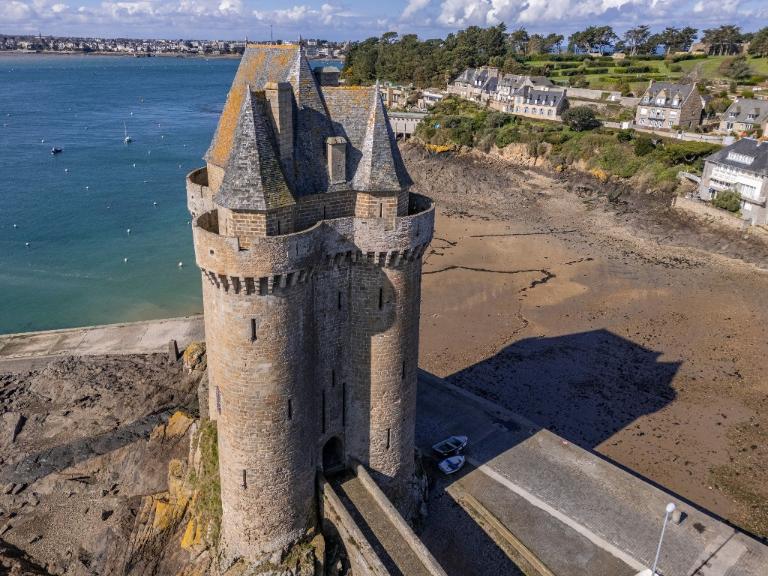 Vue aérienne oblique depuis l'est : tour et pont dormant. L'étage de comble coiffé d'un toit conique complexe en ardoise 