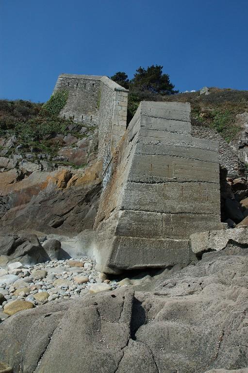 Vue de l'extrémité ouest de la batterie basse du Mengant depuis la grève à marée basse : partie consolidée en béton armé (état en 2005). Au-dessus, la branche tombante ouest percée de créneaux de tir