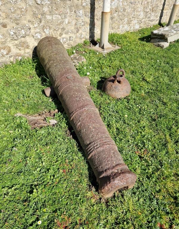 Vue d'un tube de canon de marine et d'une bombe pour mortier (les deux ne vont pas ensemble). Ces objets sont conservés à l'air libre dans la basse-cour