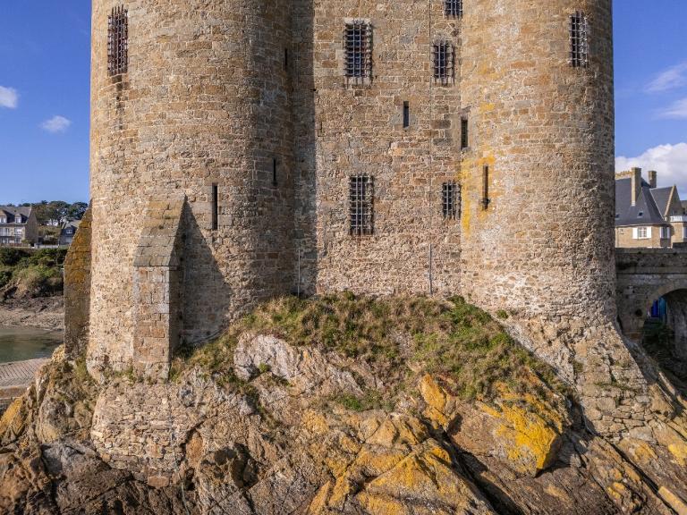 Vue aérienne oblique depuis le sud : élévation sud, détail du rez-de-chaussée et du premier étage. Un massif de maçonnerie supporte le contrefort sud de la tour ouest