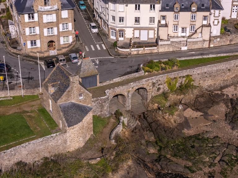Vue aérienne oblique de la basse-cour depuis le sud-est : rampe, pont, châtelet et corps de garde. En arrière-plan, Saint-Servan