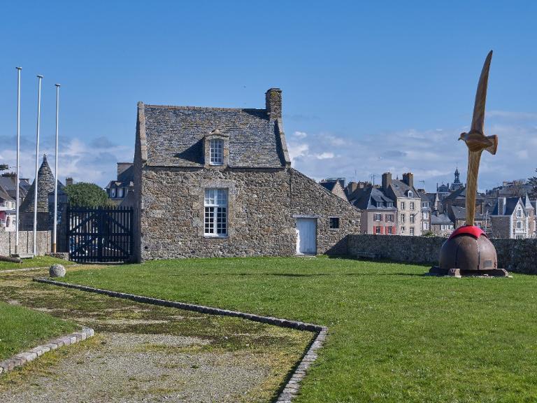 Vue du corps de garde implanté à l'entrée de la basse-cour et flanquant la porte : élévation sud-ouest. A droite, la sculpture-girouette baptisée l'Albatros