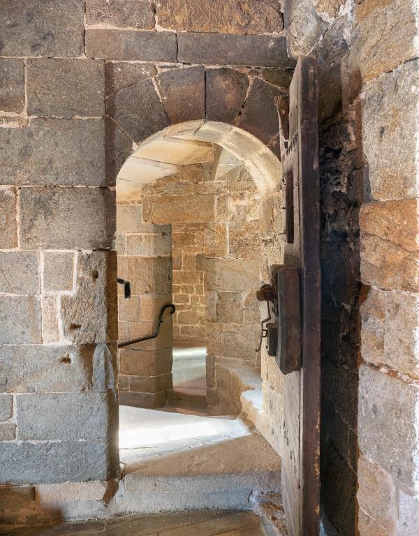 Vue intérieure de la tour Solidor : premier étage, pièce intermédiaire, porte d'accès depuis l'escalier en vis (ouverte). Le dispositif de fermeture de la porte et le judas témoignent de l'utilisation carcérale de la tour. Elle comporte des graffitis